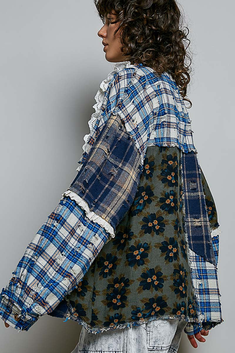 A model shown from the side/back wearing a patchwork patchwork jacket made of blue plaid and floral printed fabrics, paired with light-wash denim jeans against a plain gray studio background.