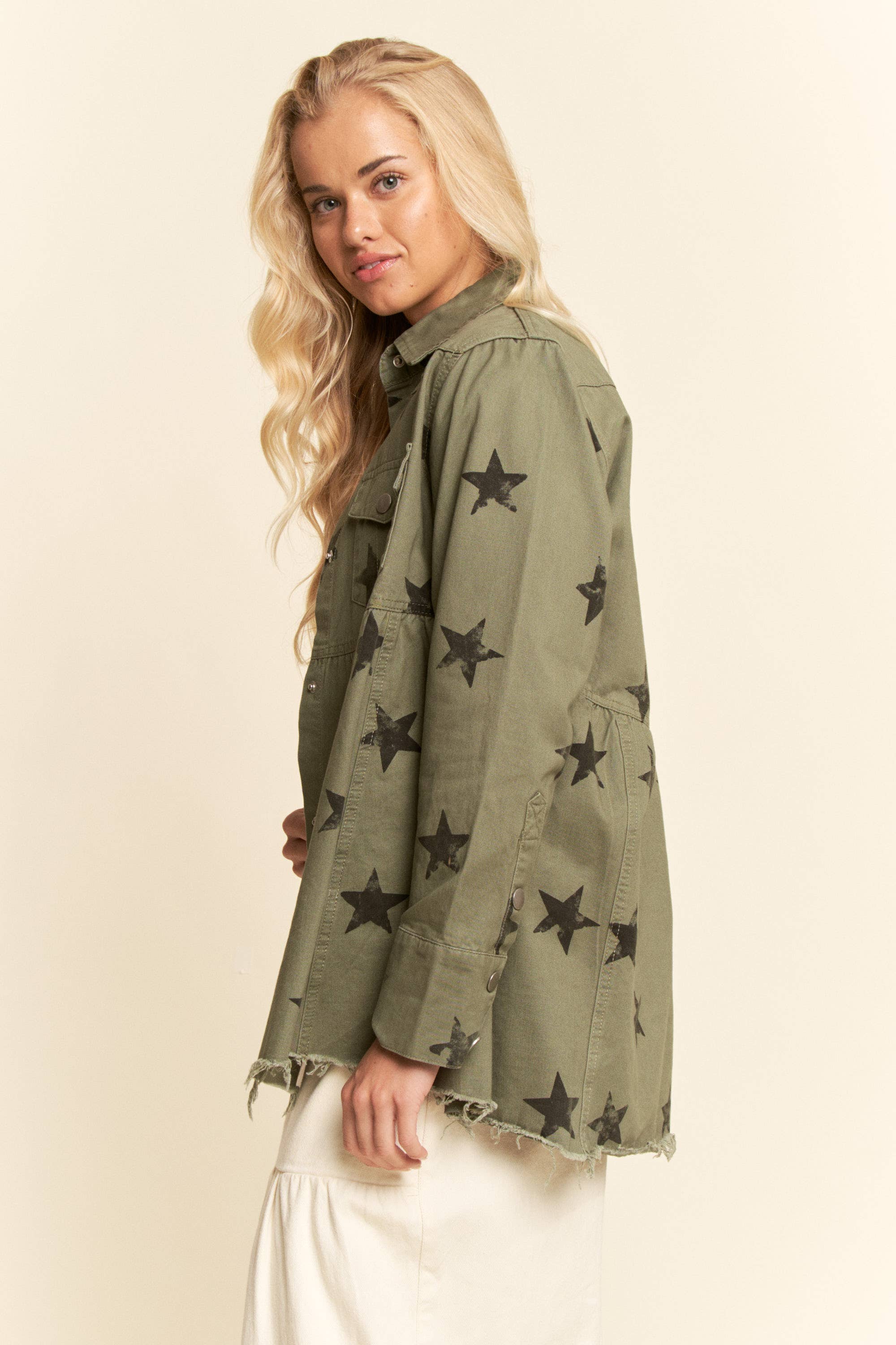 Side view- Olive star-print babydoll shacket with snap-button front, chest flap pockets, dropped shoulders, relaxed fit, and frayed curved hem.