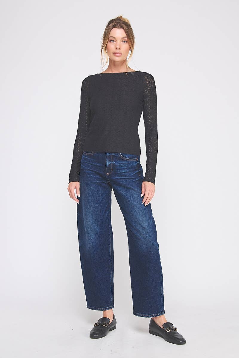 Woman wearing a black long-sleeve lace top and blue jeans on a white background