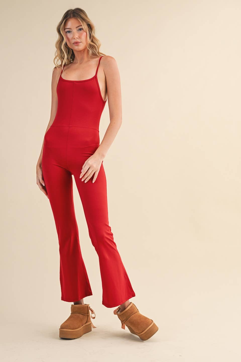 Rear view of Woman wearing Kimberly C flare jumpsuit in red with scoop neckline and flared leg.