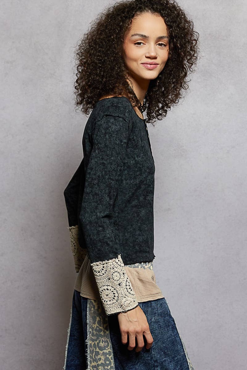 Woman wearing a dark gray sweater with lace trim on a gray background