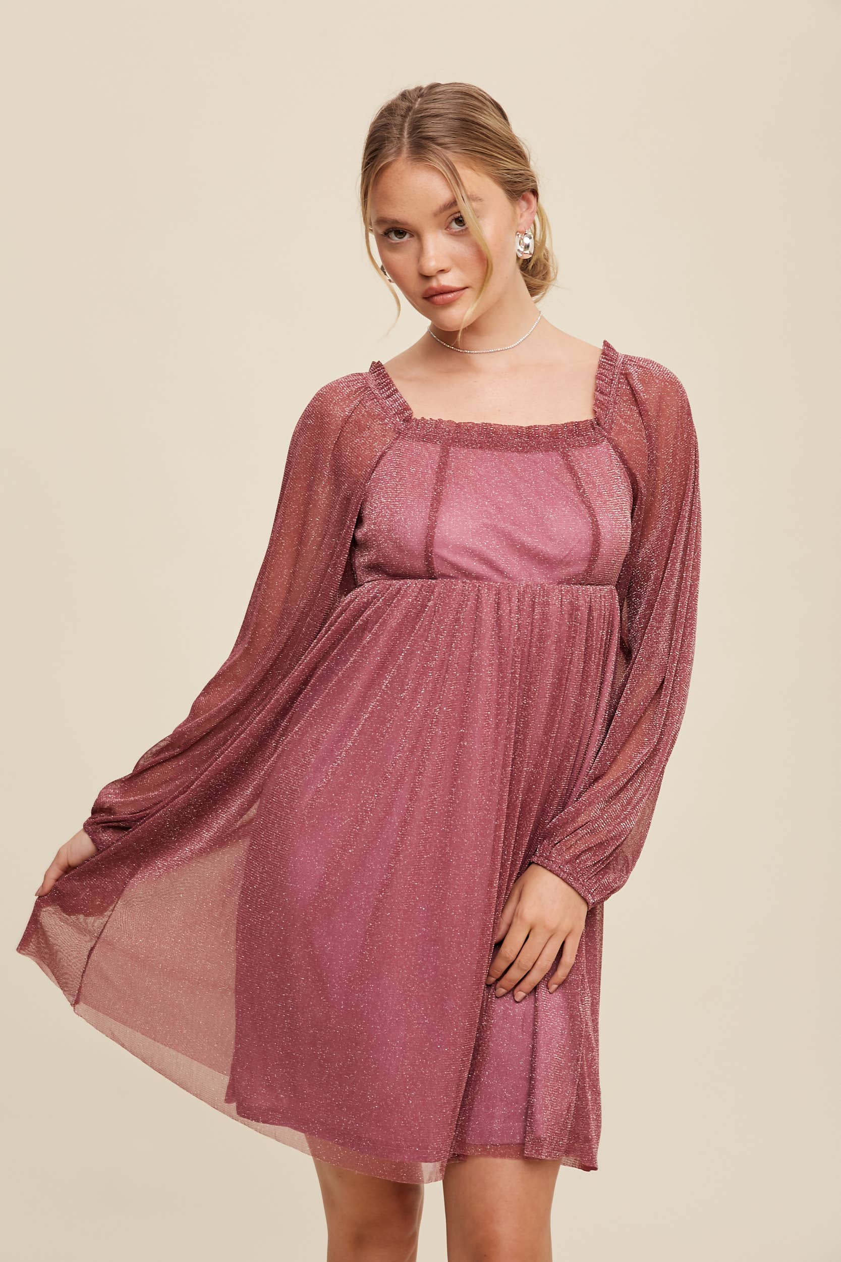 Model wearing a mauve shimmer mini dress with long sheer sleeves, square neckline, and flowy A-line silhouette — romantic sparkle party dress