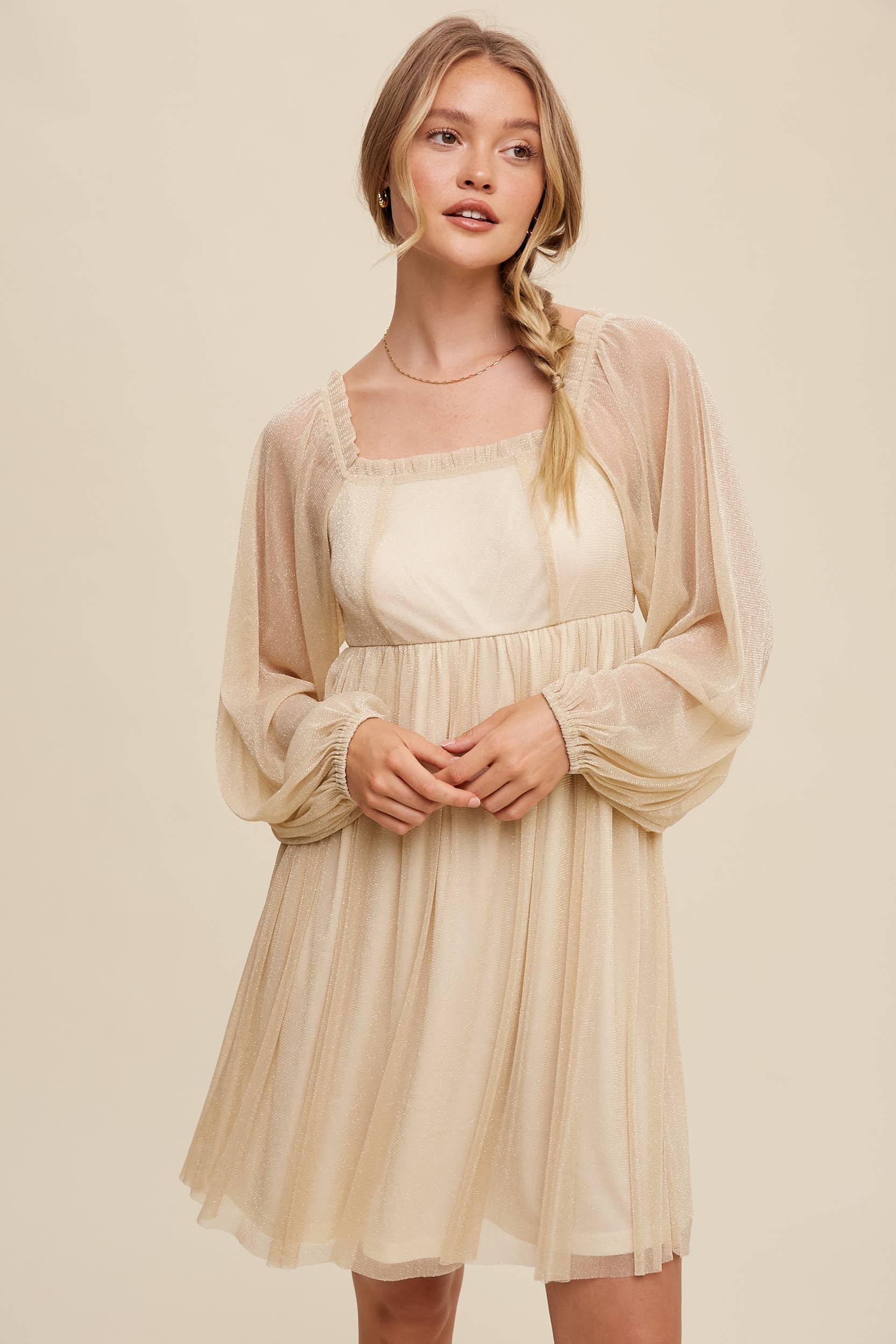Model wearing a beige shimmer mini dress with long sheer sleeves, square neckline, and flowy A-line silhouette — romantic sparkle party dress