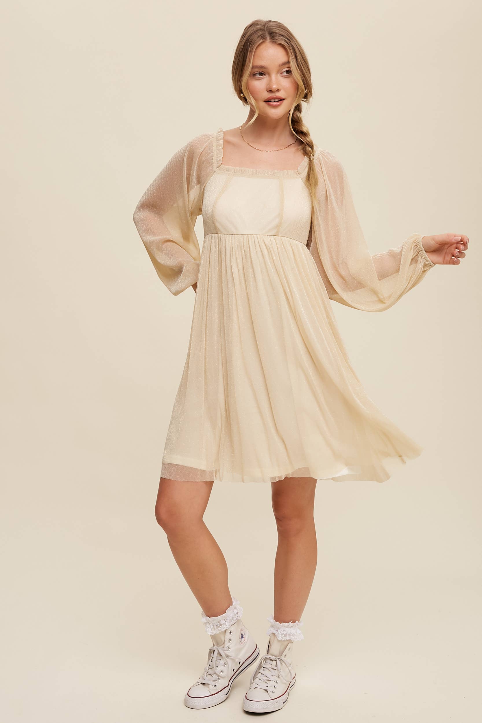 Model wearing a beige shimmer mini dress with long sheer sleeves, square neckline, and flowy A-line silhouette — romantic sparkle party dress