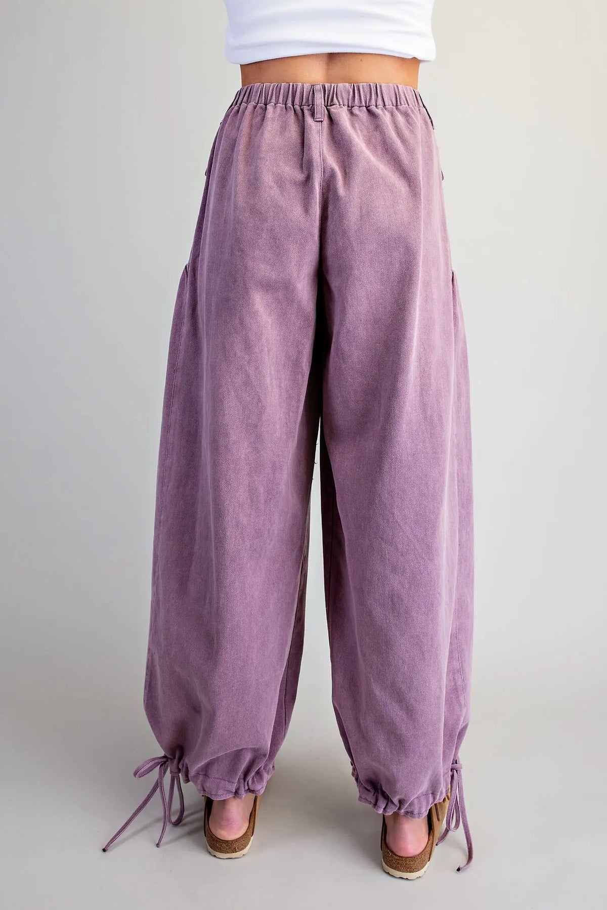 Back view of women's plum mineral washed relaxed tie cuff pants — wide-leg boho silhouette with elastic waistband and drawstring ankle ties