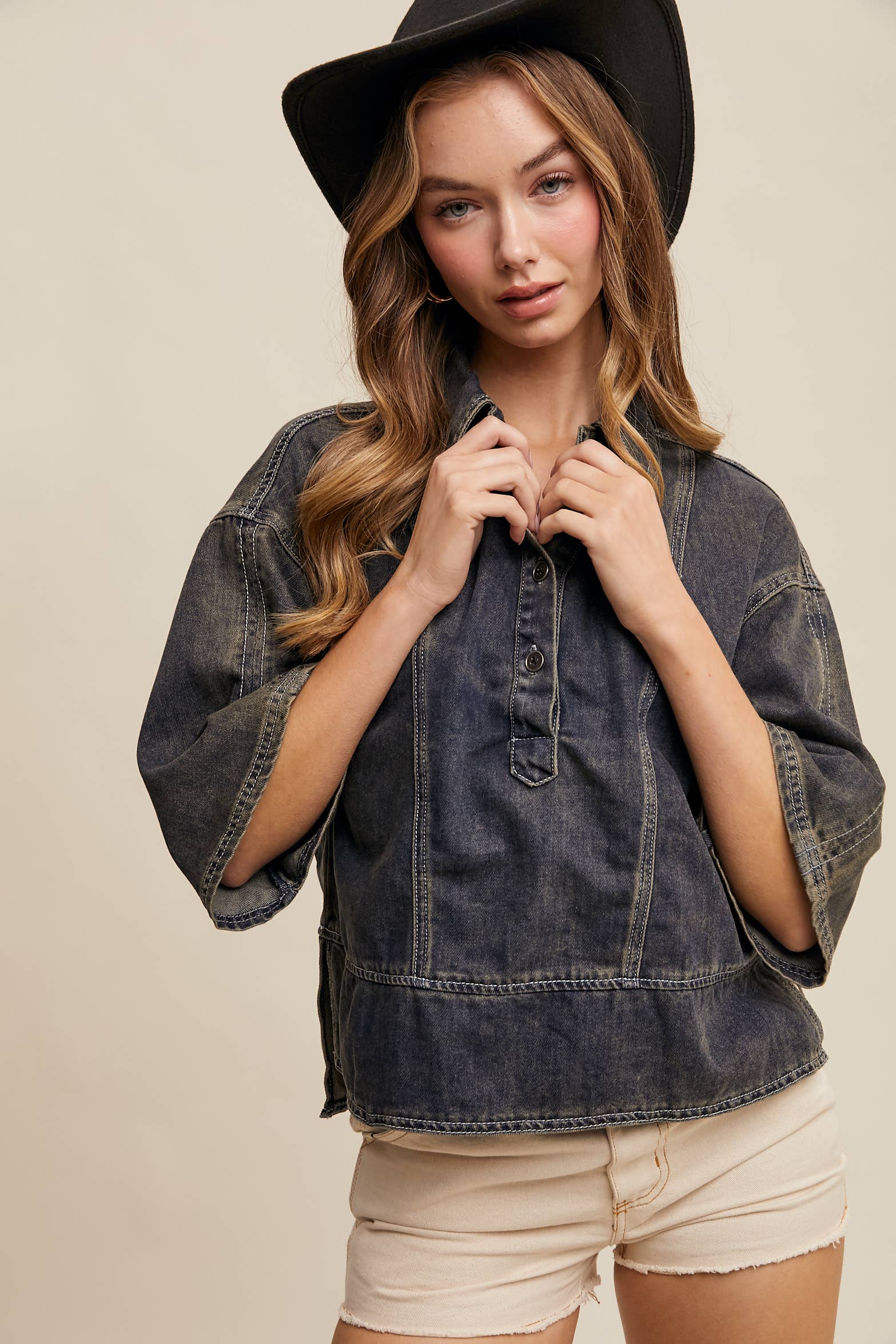 Dark-wash denim pullover top with half-button placket, exposed seam panels, and wide elbow-length sleeves in a relaxed, boxy fit.