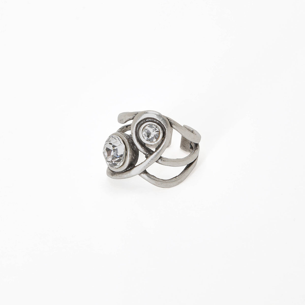 A silver-toned ring featuring two round clear gemstones in a swirling, openwork design, photographed on a seamless white background.