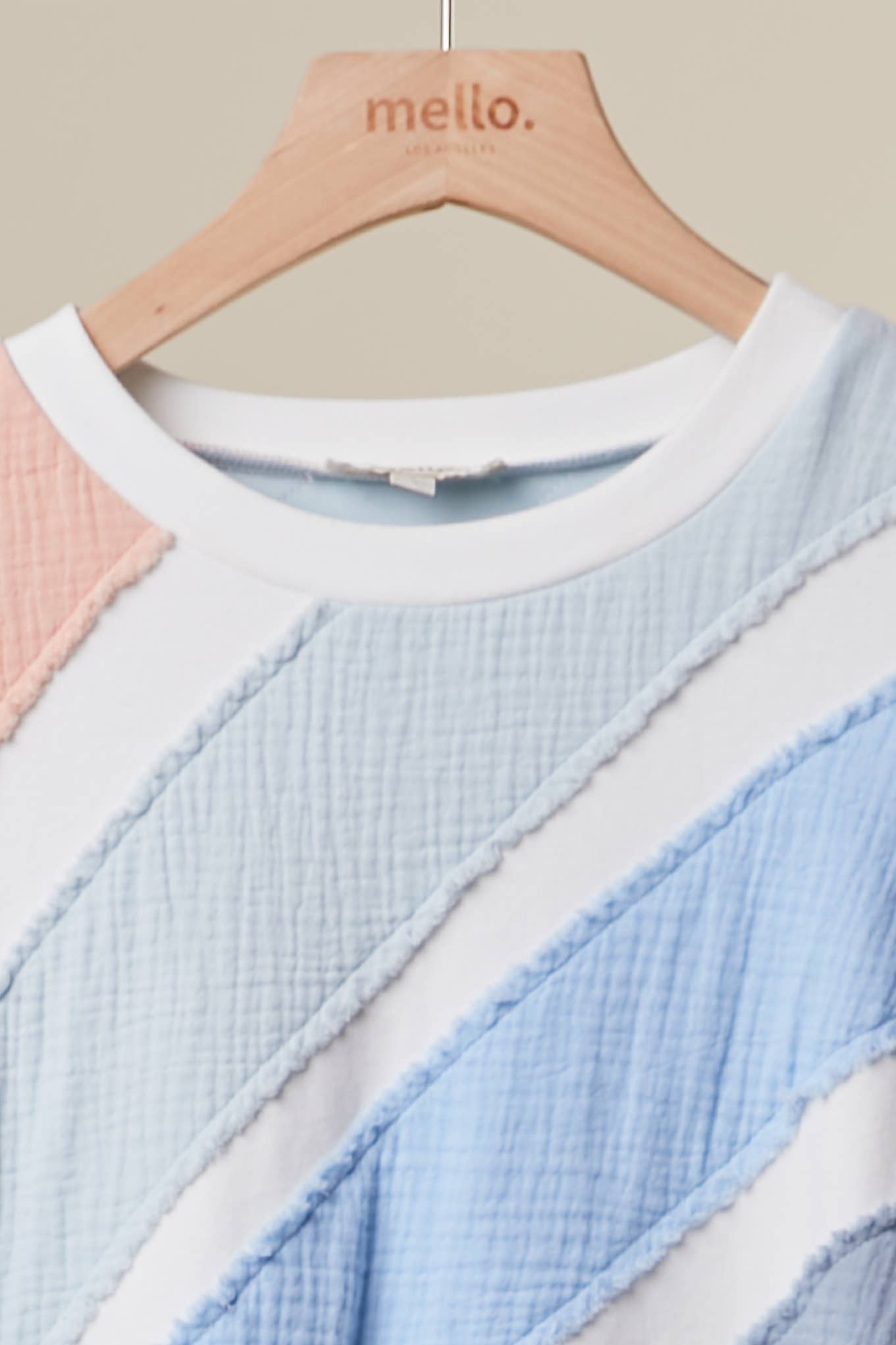 Color-blocked sweater on a hanger with 'mello.' branding