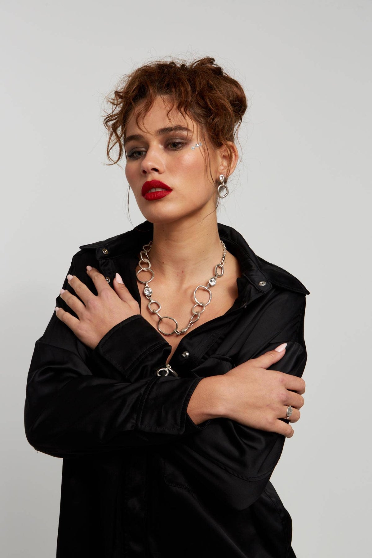 Woman wearing a black shirt and silver necklace against a gray background