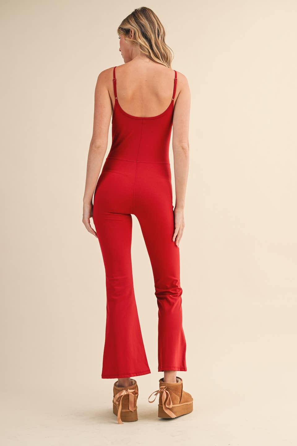 Rear view of Woman wearing Kimberly C flare jumpsuit in red with scoop neckline and flared leg.