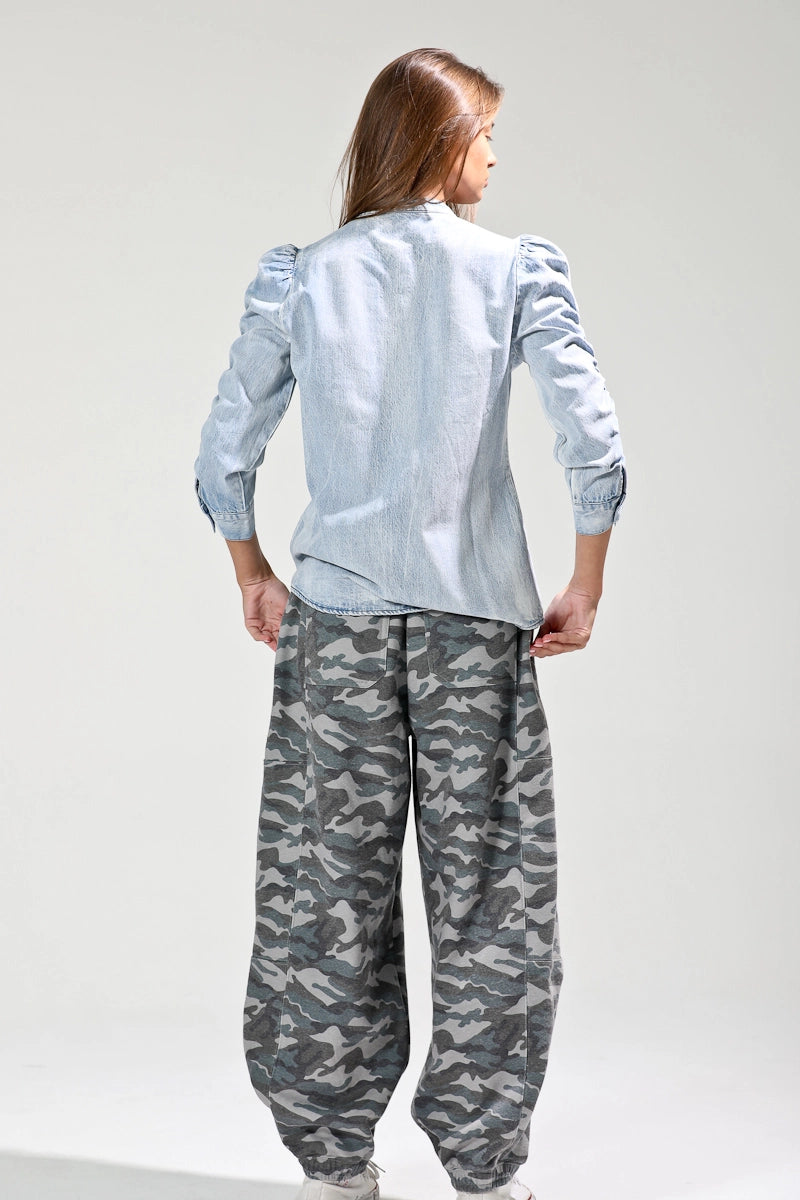 Person wearing a light blue shirt and camouflage pants on a white background