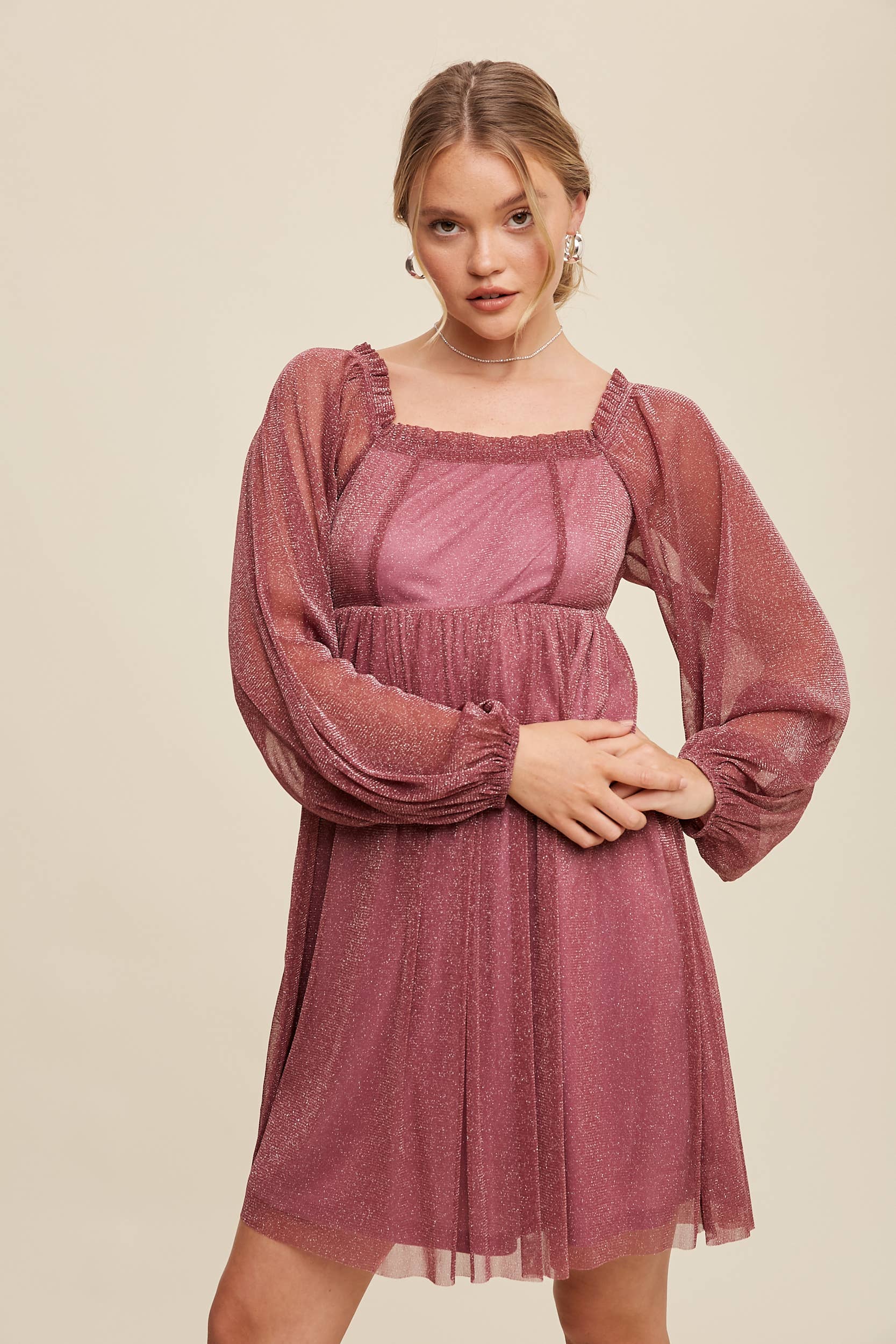 Model wearing a mauve shimmer mini dress with long sheer sleeves, square neckline, and flowy A-line silhouette — romantic sparkle party dress