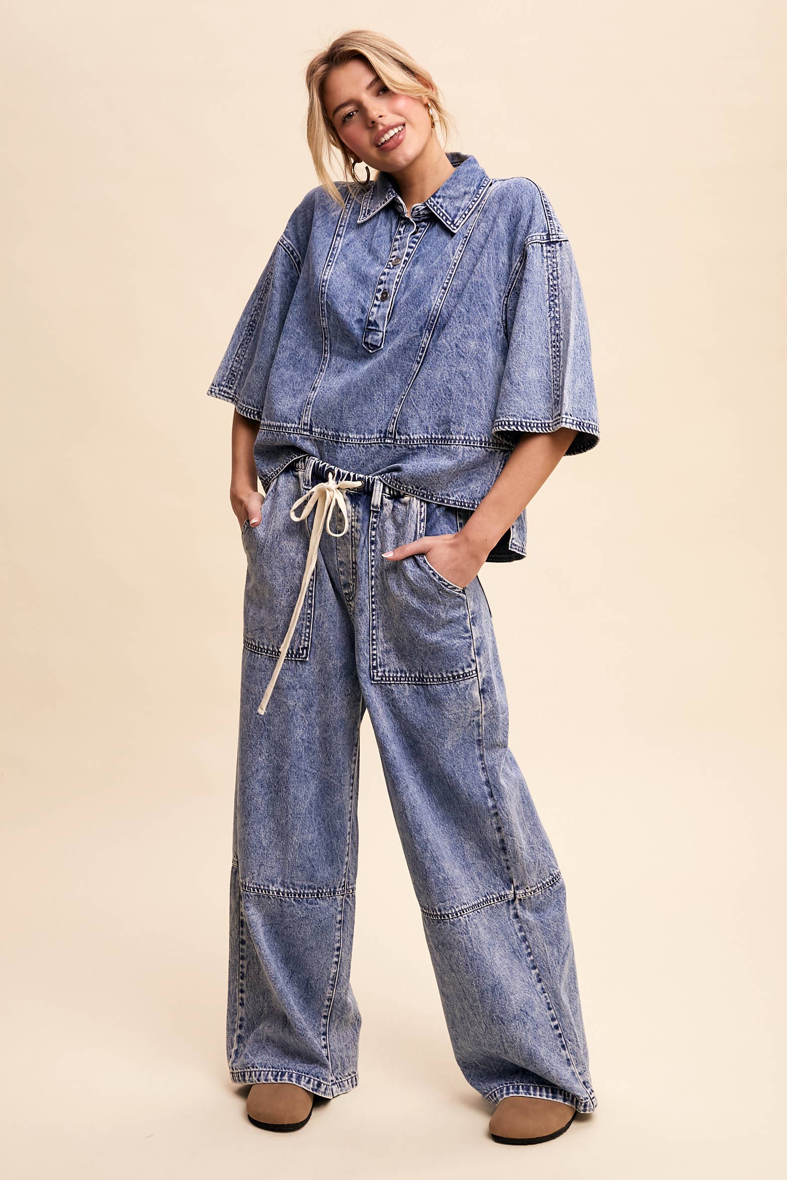 Light-wash denim pullover top with a half-button placket, exposed seam panels, and wide elbow-length sleeves in a relaxed, boxy fit.