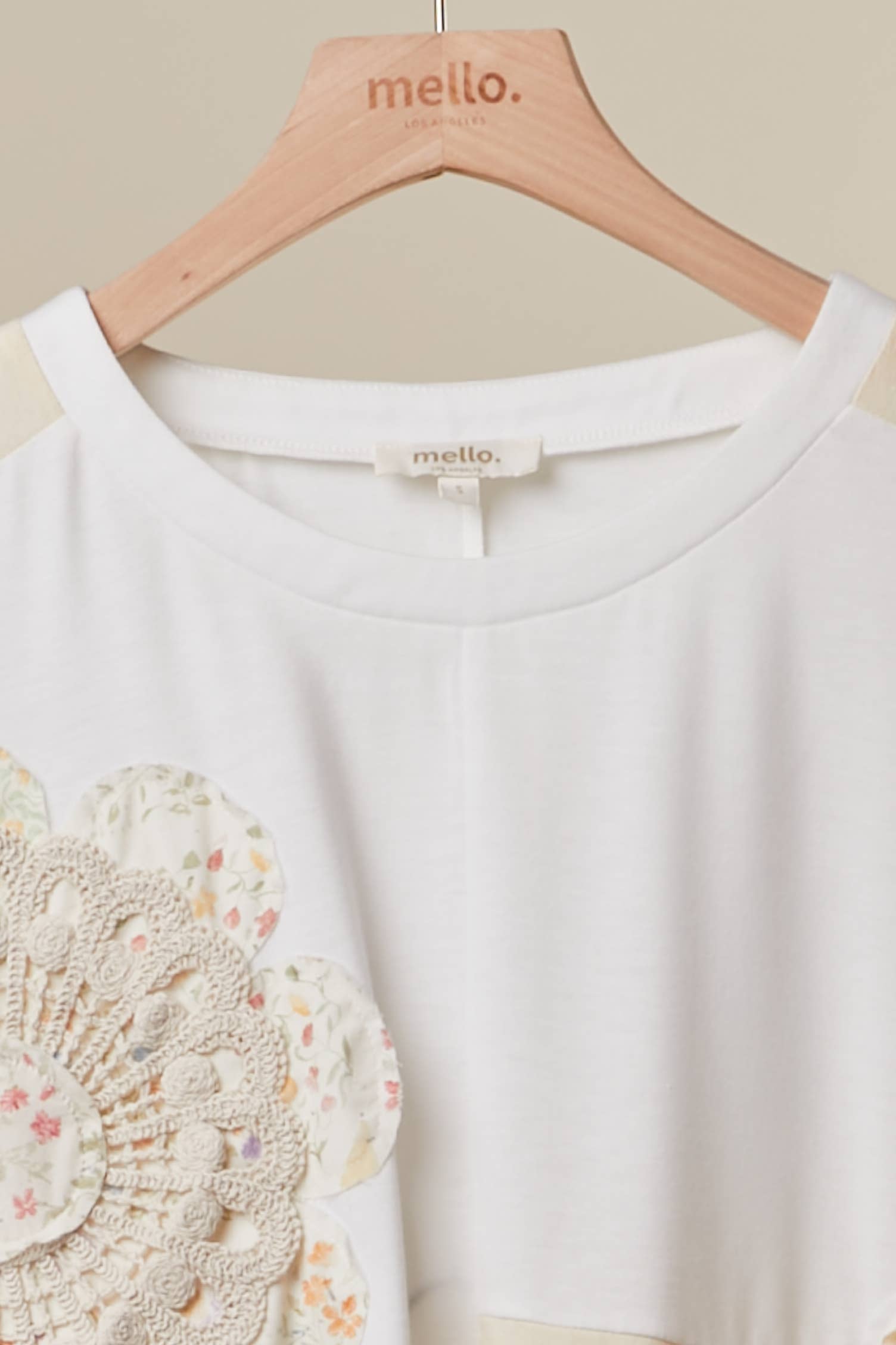 Close up of The Cleo Crochet Patchwork Top in Cream — oversized patchwork silhouette with crochet medallion patch and flower appliqué detail, boho-luxe ivory and cream colorblock top