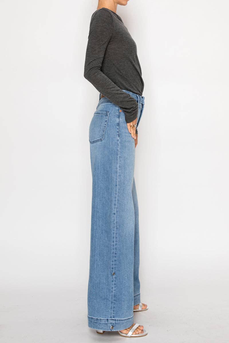 Side view of model wearing ultra high-rise wide-leg jeans in medium stone wash with cuff detail and button accents along the leg