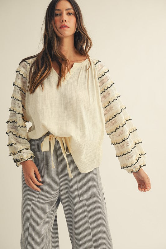 Front view of cream gauze peasant blouse with embroidered scalloped-stripe balloon sleeves, notched neckline, and tie waist.