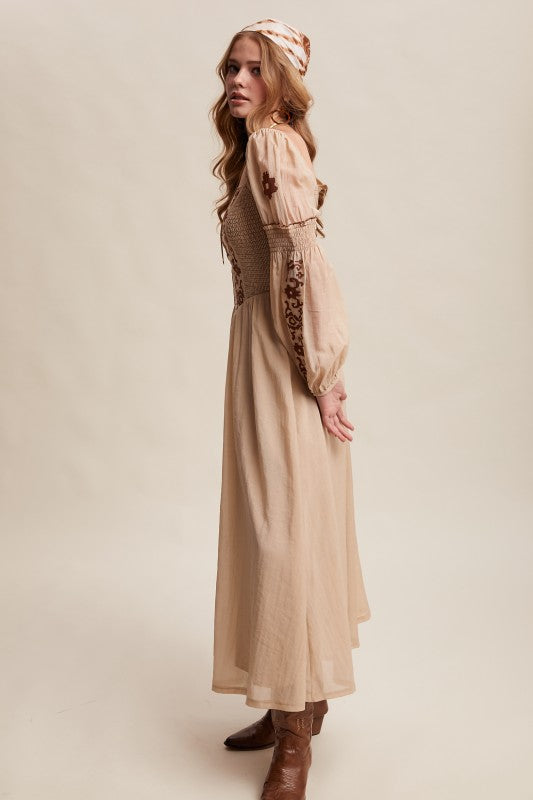 Side view of beige boho maxi dress with embroidered sleeves and smocked bodice.
