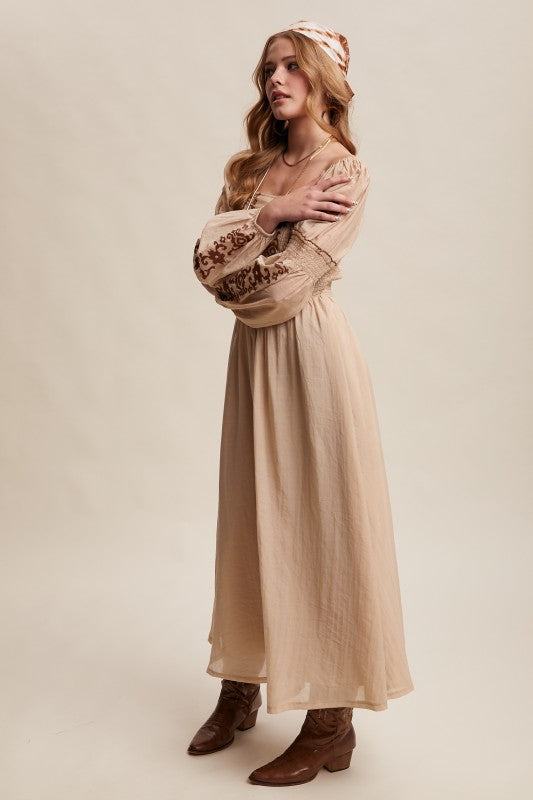 Side view of beige boho maxi dress with embroidered sleeves and smocked bodice.