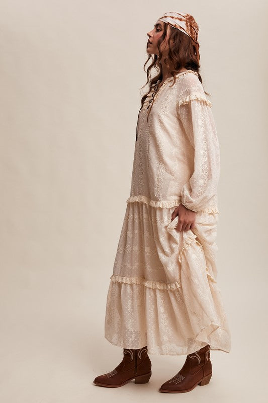 Side view of model in ivory lace boho maxi dress with ruffle tiers, headscarf, and brown western boots.