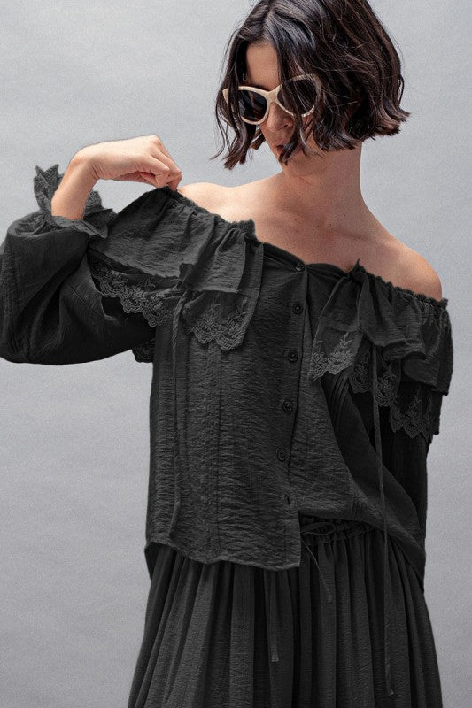 Close-up of romantic lace detailing and layered ruffles on black off-shoulder blouse