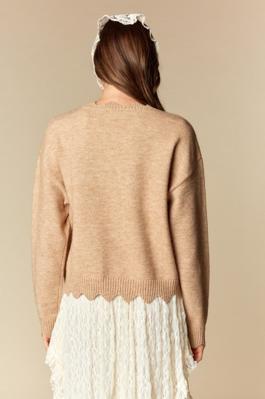 Camel knit sweater with white lace bow applique, relaxed fit, ribbed cuffs and scalloped hem, three-quarter back view on model.