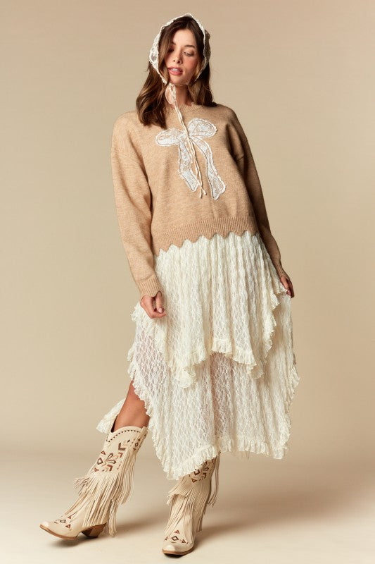 Camel knit sweater with white lace bow applique, relaxed fit, ribbed cuffs and scalloped hem, three-quarter front view on model.