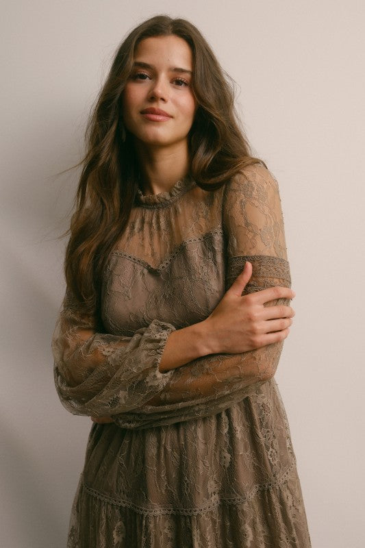 Woman wearing Angelica tiered lace maxi dress with long mesh sleeves and floral lace overlay, romantic boho-inspired style, styled for weddings, showers, or date nights.