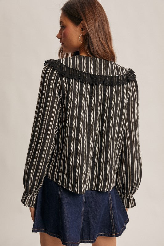 Back view of black striped blouse with lace ruffle collar and long sleeves.