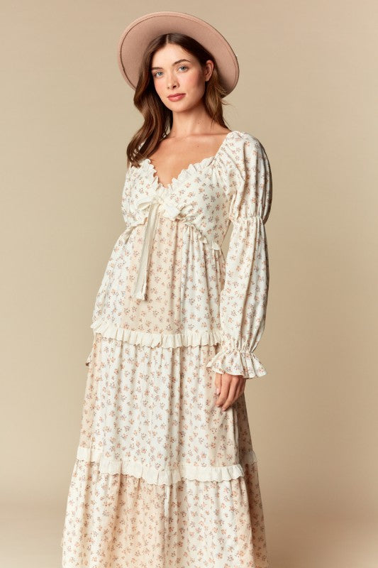 Front view — cream/blush ditsy floral tiered maxi dress with ruffle trim, long puff sleeves, tie-front sweetheart neckline.