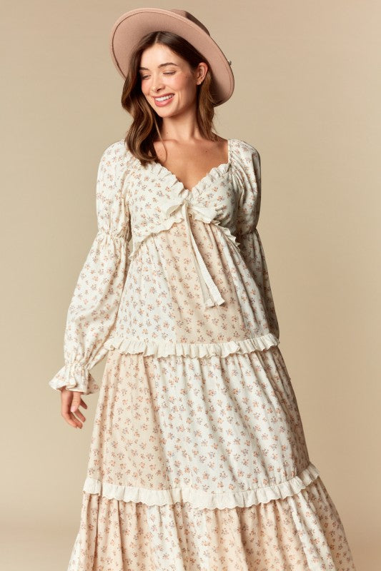 Front view — cream/blush ditsy floral tiered maxi dress with ruffle trim, long puff sleeves, tie-front sweetheart neckline.