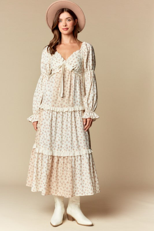 Front view — cream/blush ditsy floral tiered maxi dress with ruffle trim, long puff sleeves, tie-front sweetheart neckline.