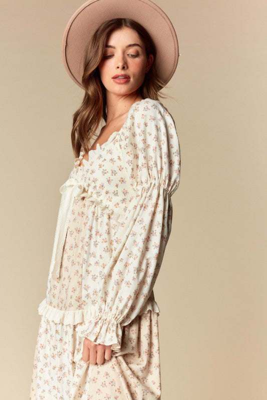 Side view — cream/blush ditsy floral tiered maxi dress with ruffle trim, long puff sleeves, tie-front sweetheart neckline.