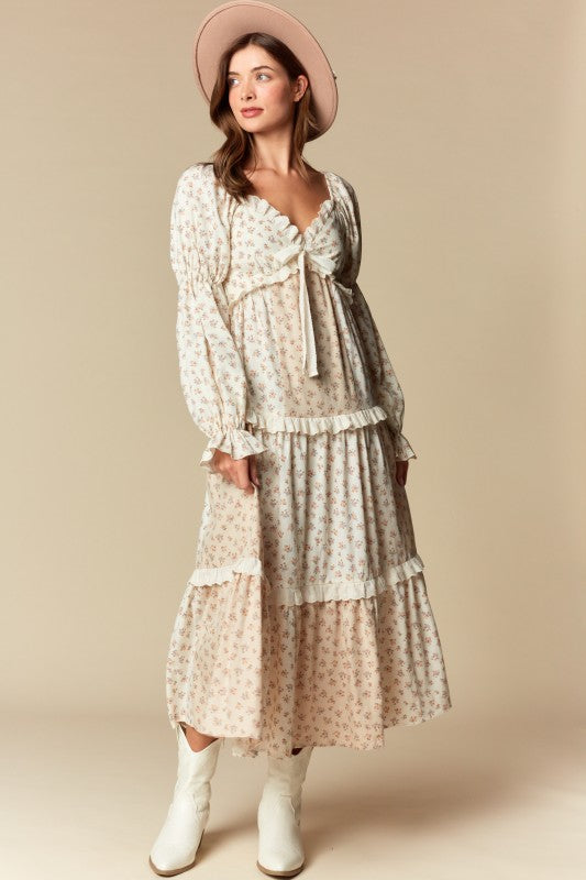 Front view — cream/blush ditsy floral tiered maxi dress with ruffle trim, long puff sleeves, tie-front sweetheart neckline.