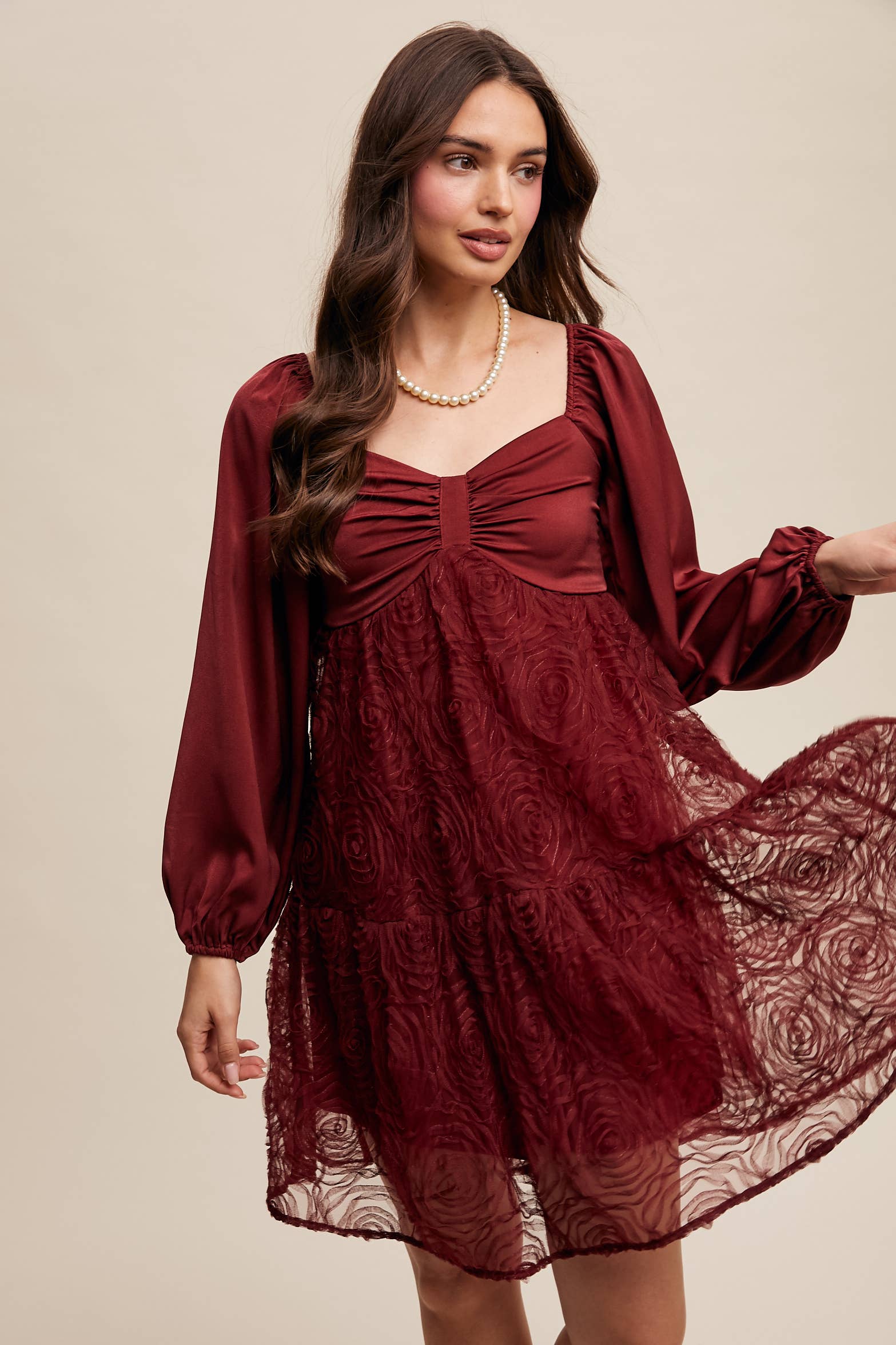 Model wearing oxblood red rosette mini dress with ruched sweetheart neckline, puff long sleeves, and tiered lace skirt — elegant and romantic look.