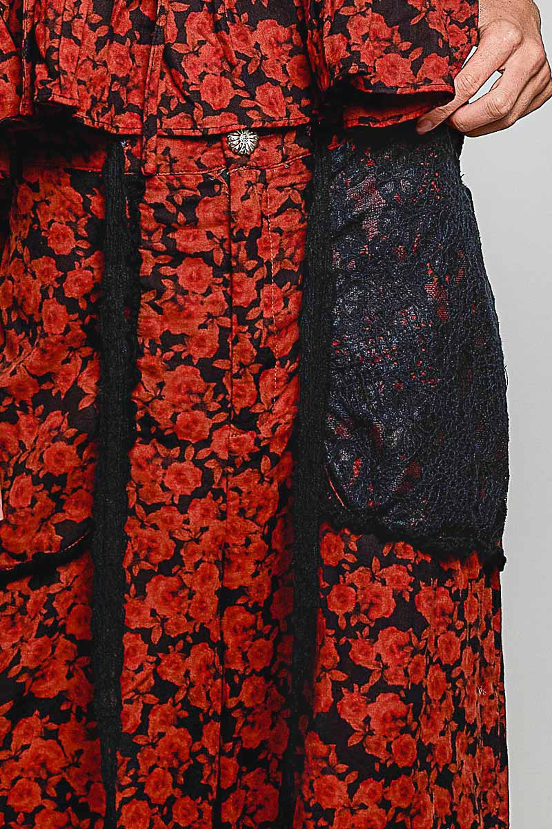 Close-up of a red and black floral dress with a black lace panel and a decorative silver button.