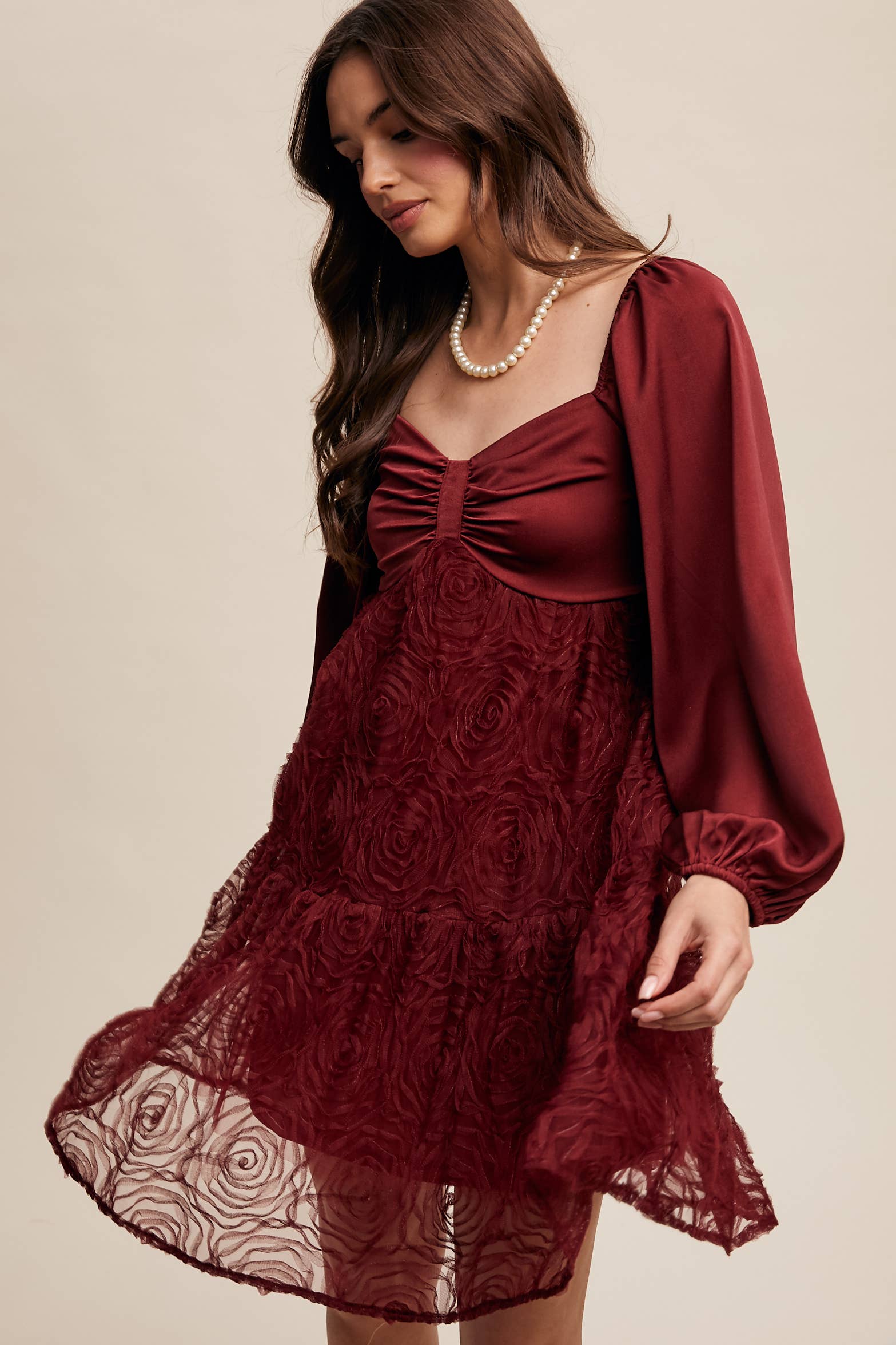 Model wearing oxblood red rosette mini dress with ruched sweetheart neckline, puff long sleeves, and tiered lace skirt — elegant and romantic look.