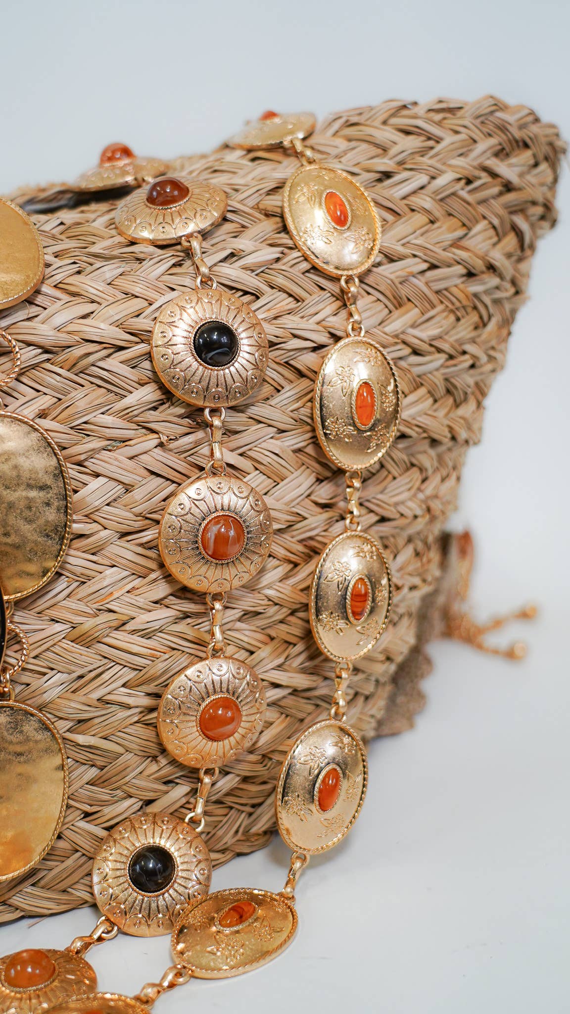 Gold belt with circular pendants on a woven bag