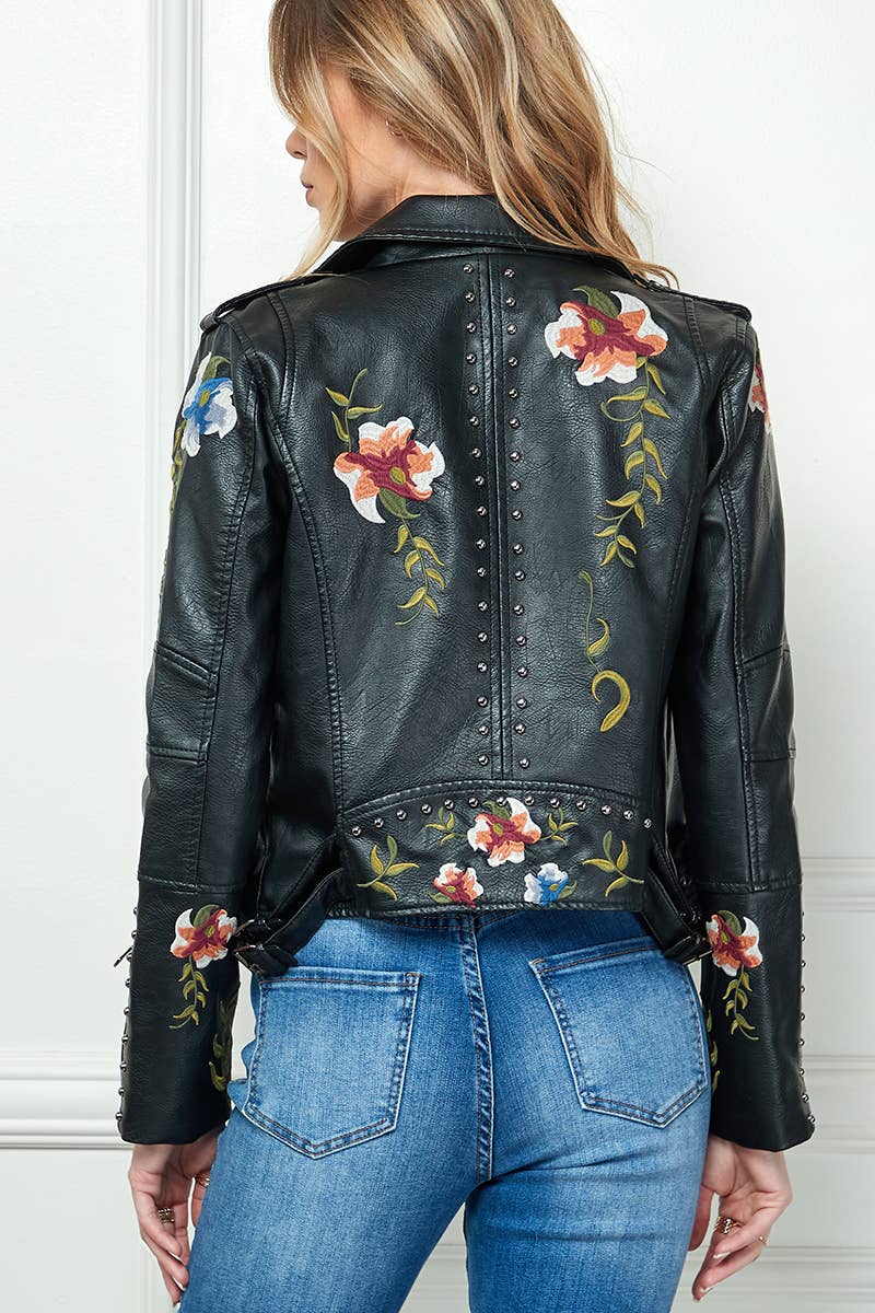 Back view of black faux-leather moto jacket with floral embroidery and silver stud trim, styled with blue jeans.