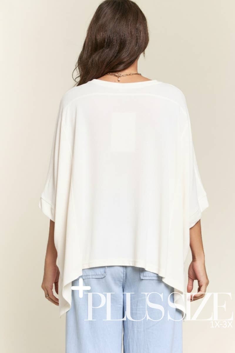 Woman wearing a white oversized top and light blue jeans on a beige background with 'Plus Size' text.