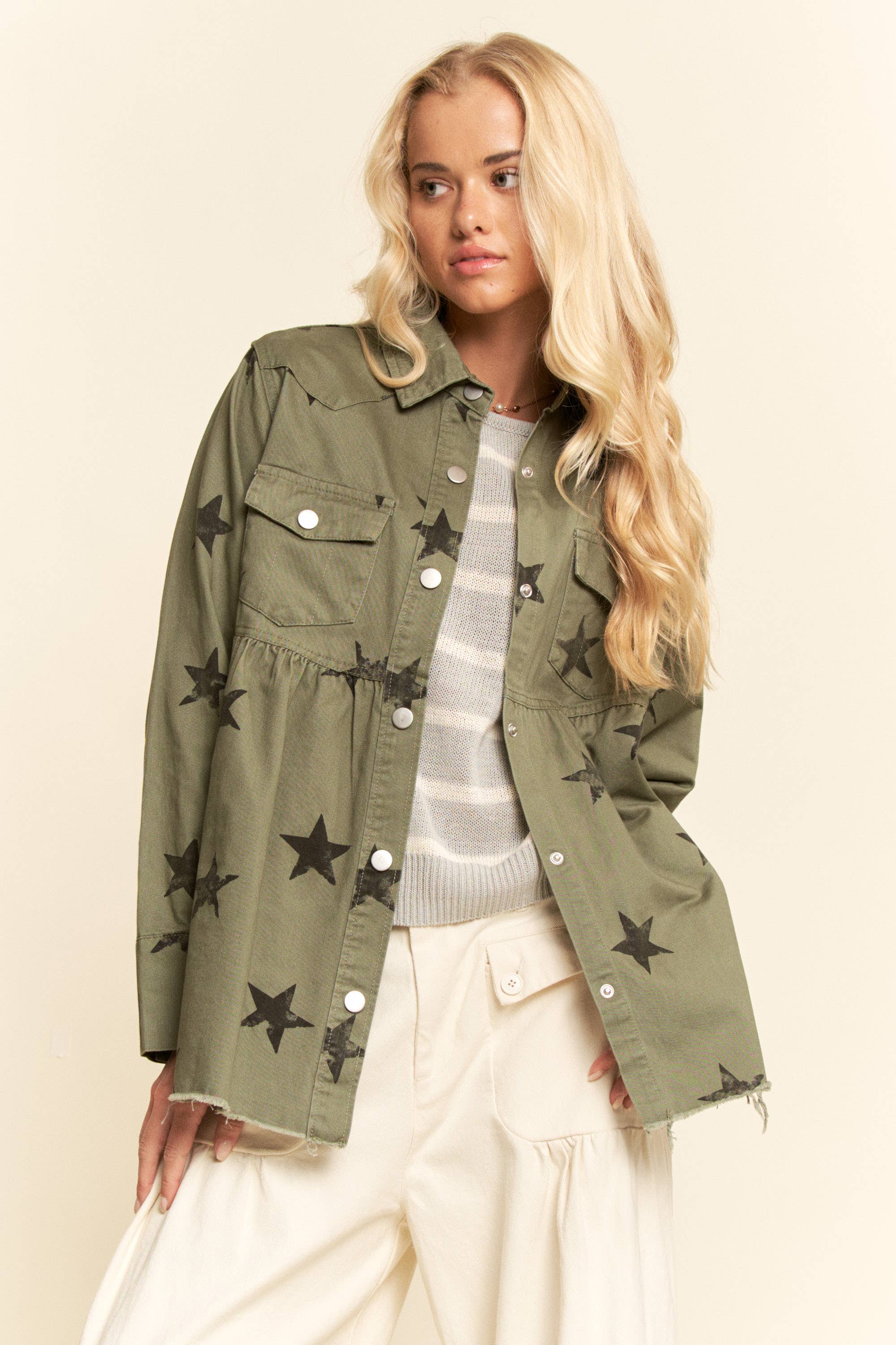 Olive star-print babydoll shacket with snap-button front, chest flap pockets, dropped shoulders, relaxed fit, and frayed curved hem.