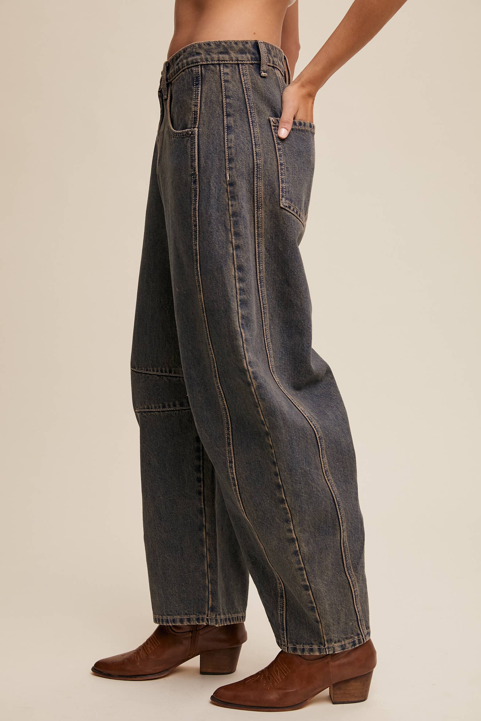 Side view- Dark wash wide-leg jeans with relaxed fit, seam detailing across the knees, and a high-rise waist, styled with brown ankle boots.