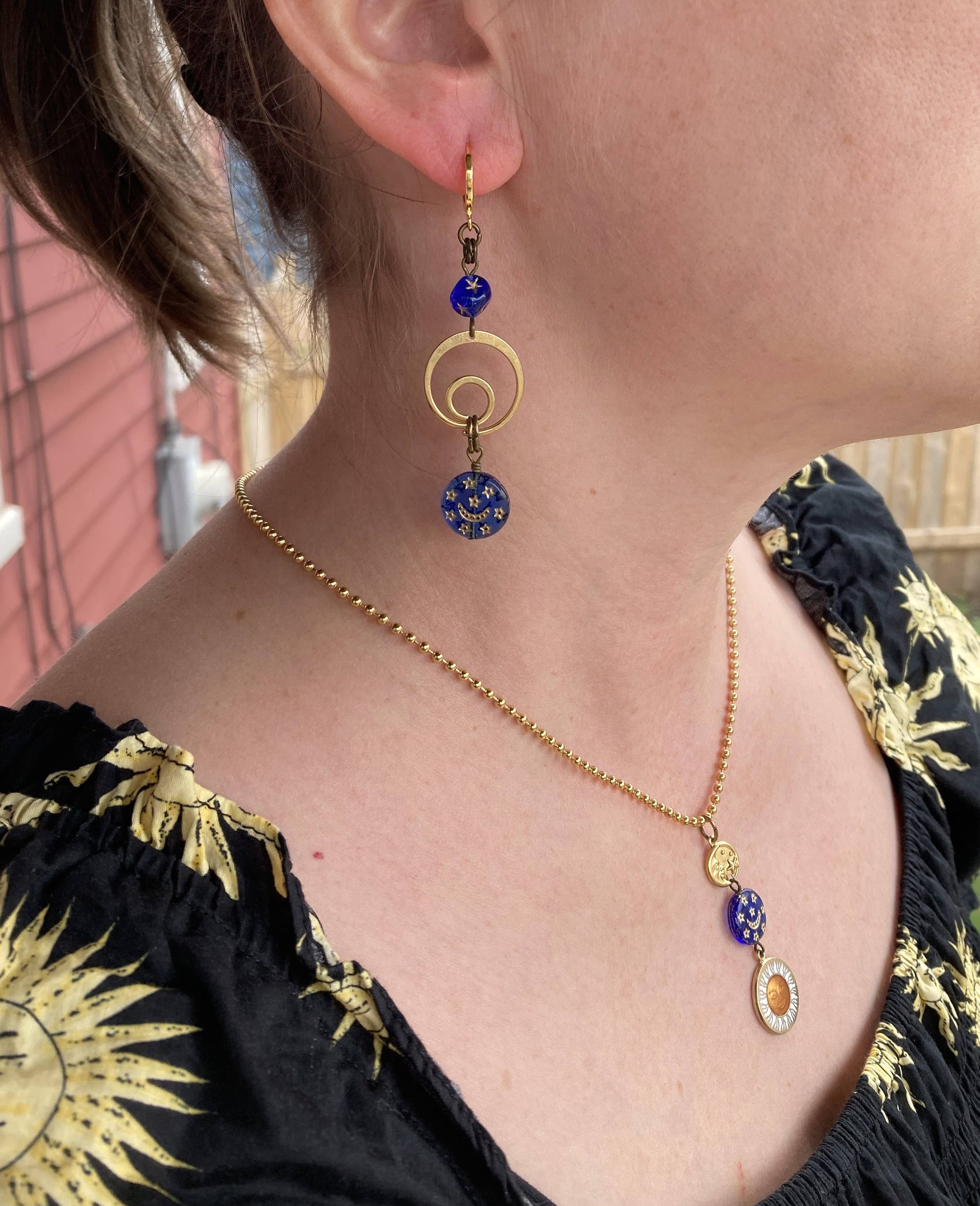 Artisan dangle earrings featuring gold rings, blue glass beads, and night sky charms.