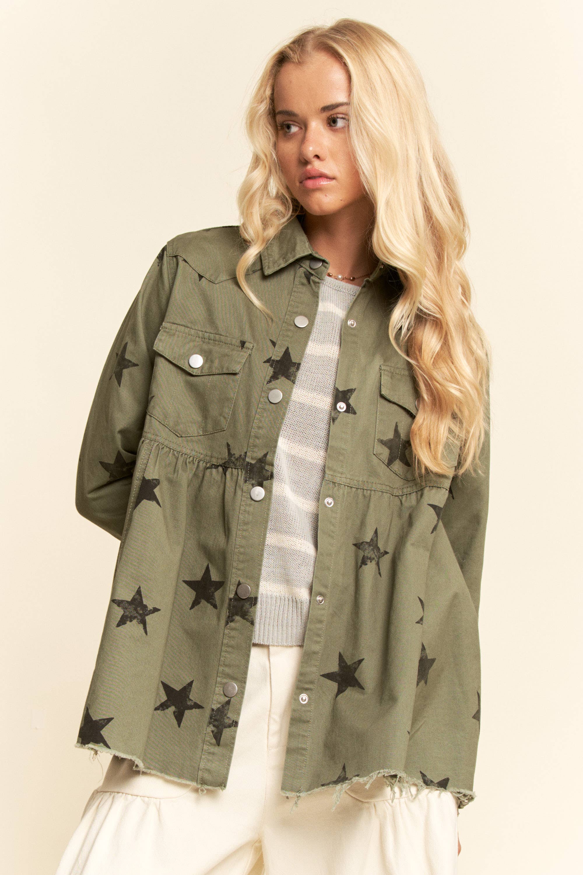 Olive star-print babydoll shacket with snap-button front, chest flap pockets, dropped shoulders, relaxed fit, and frayed curved hem.
