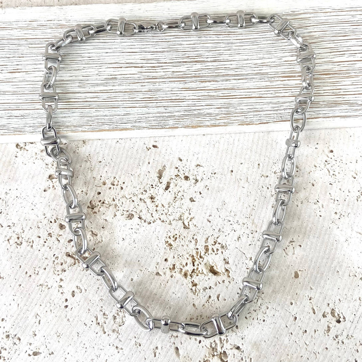 Silver chain necklace on a textured white surface