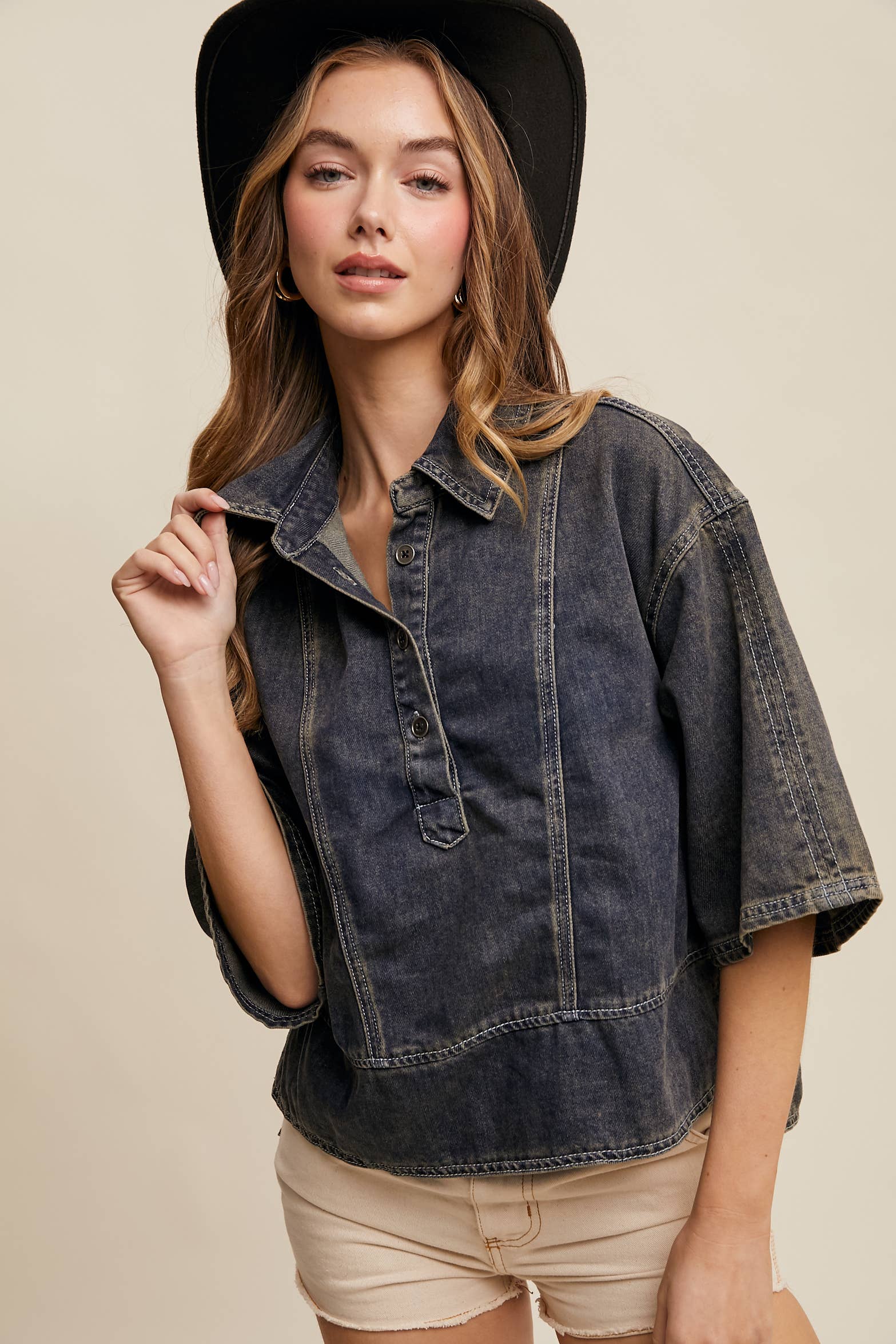Dark-wash denim pullover top with half-button placket, exposed seam panels, and wide elbow-length sleeves in a relaxed, boxy fit.