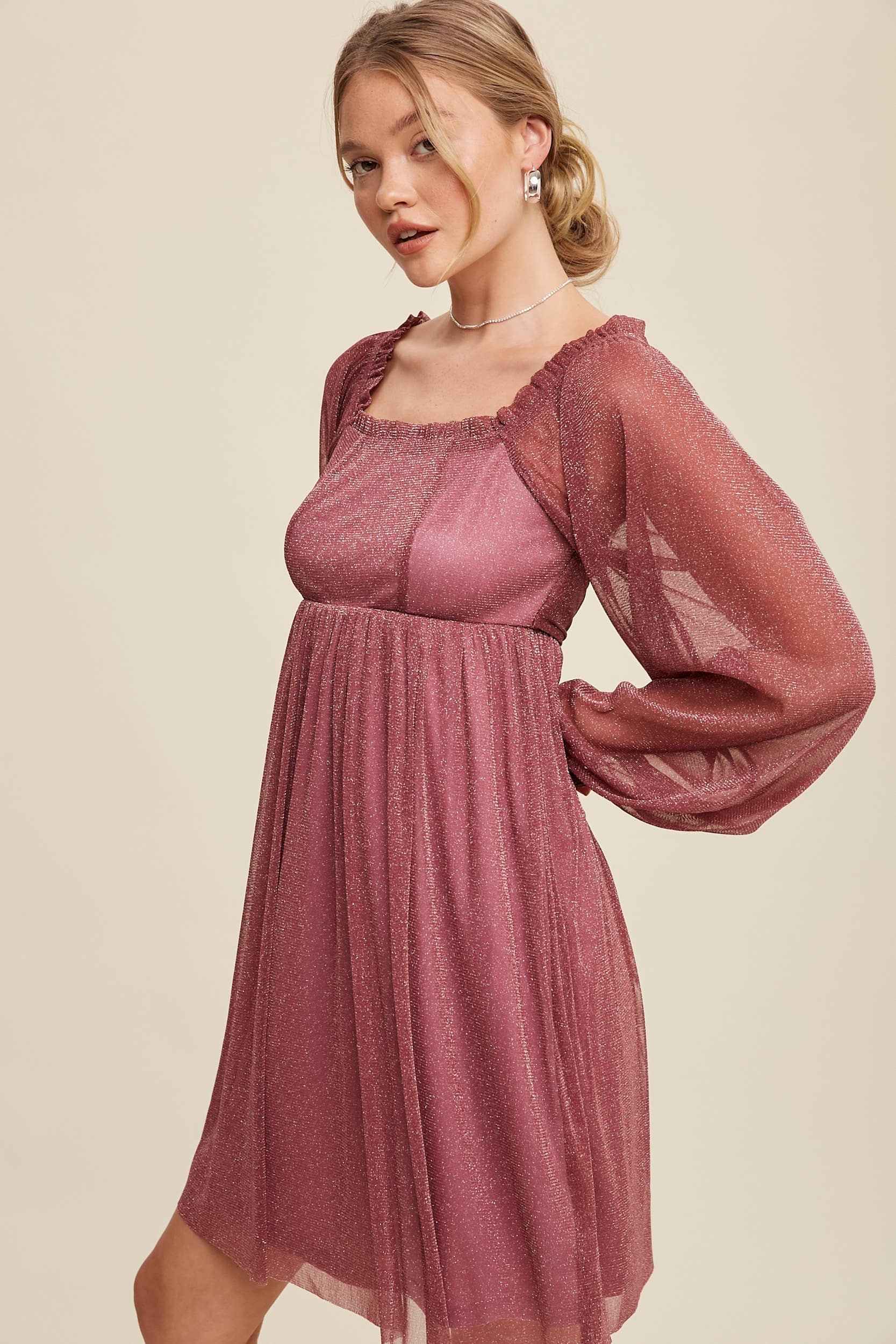 Model wearing a mauve shimmer mini dress with long sheer sleeves, square neckline, and flowy A-line silhouette — romantic sparkle party dress
