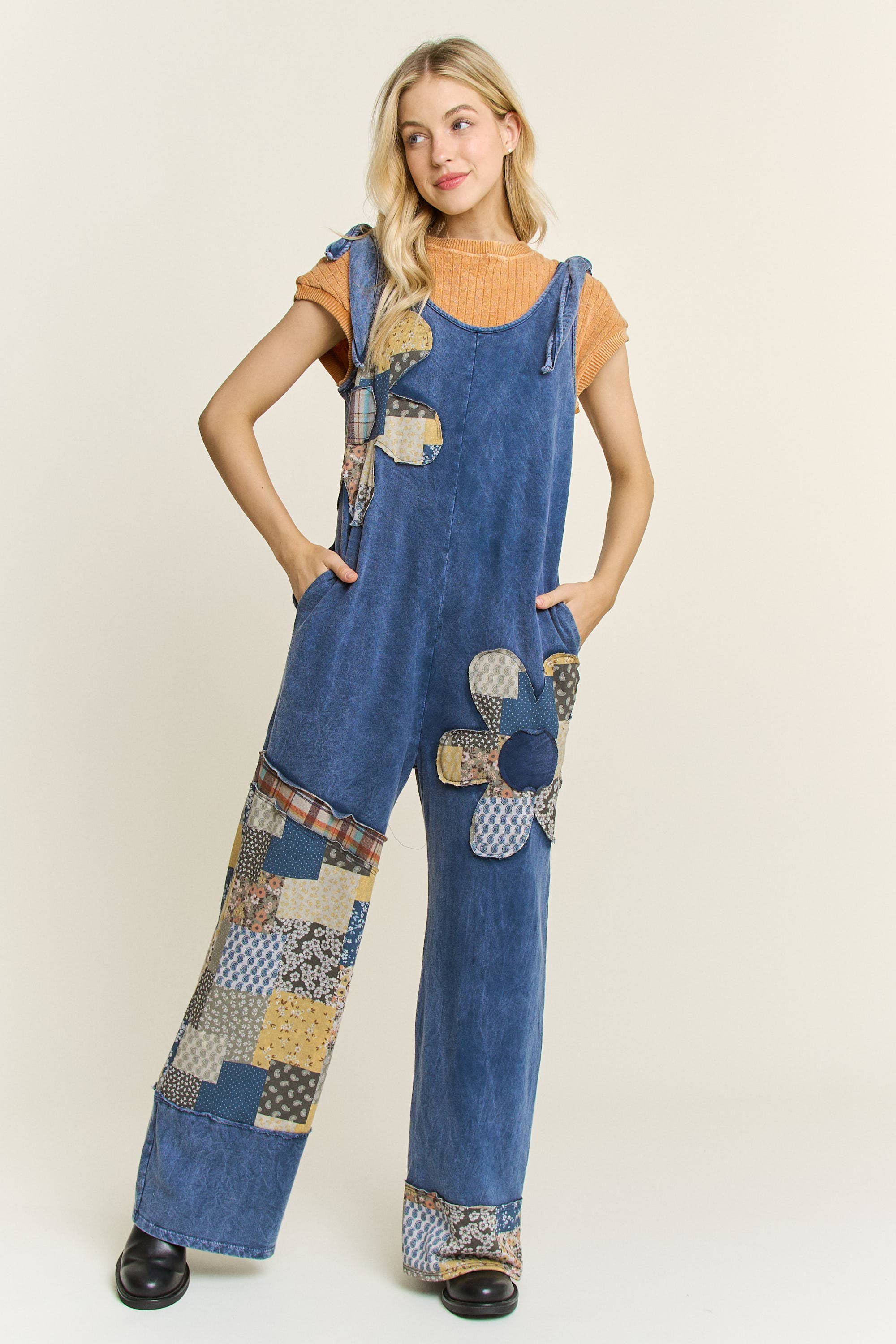 Woman wearing boho patchwork mineral-wash jumpsuit in navy with daisy appliqués and wide legs.