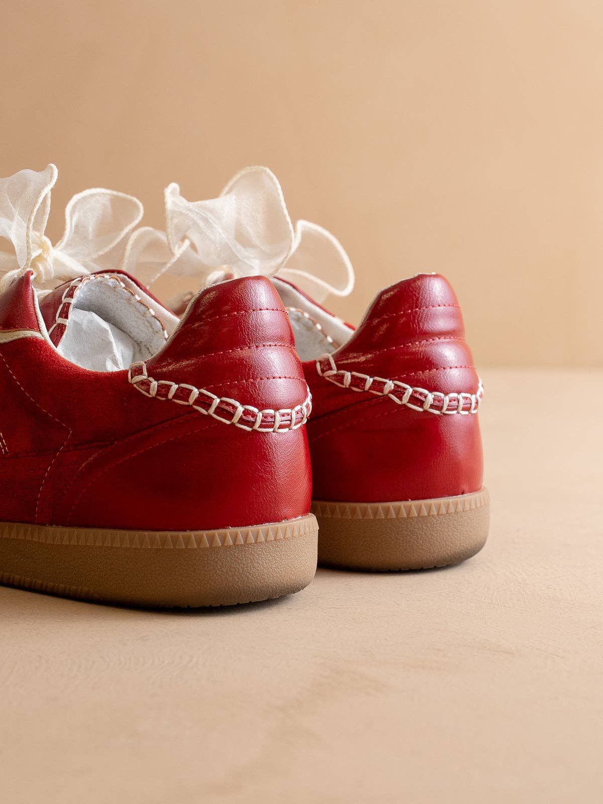 Cherry red Oasis Society sneakers with cream detailing and two lace options — organza ribbon and classic cotton.