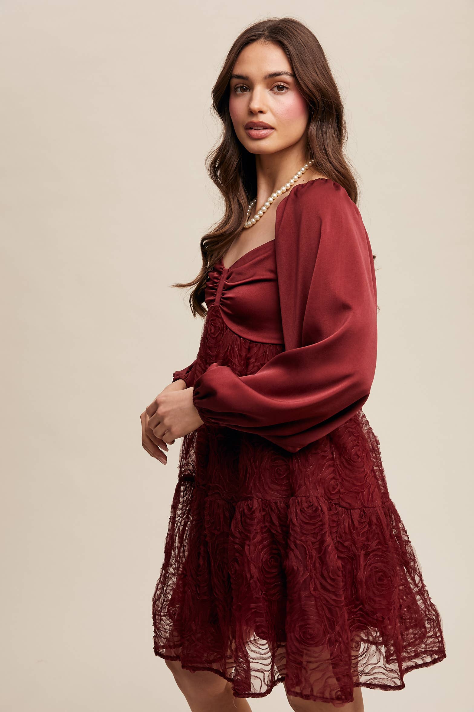 Side view of Model wearing oxblood red rosette mini dress with ruched sweetheart neckline, puff long sleeves, and tiered lace skirt — elegant and romantic look.
