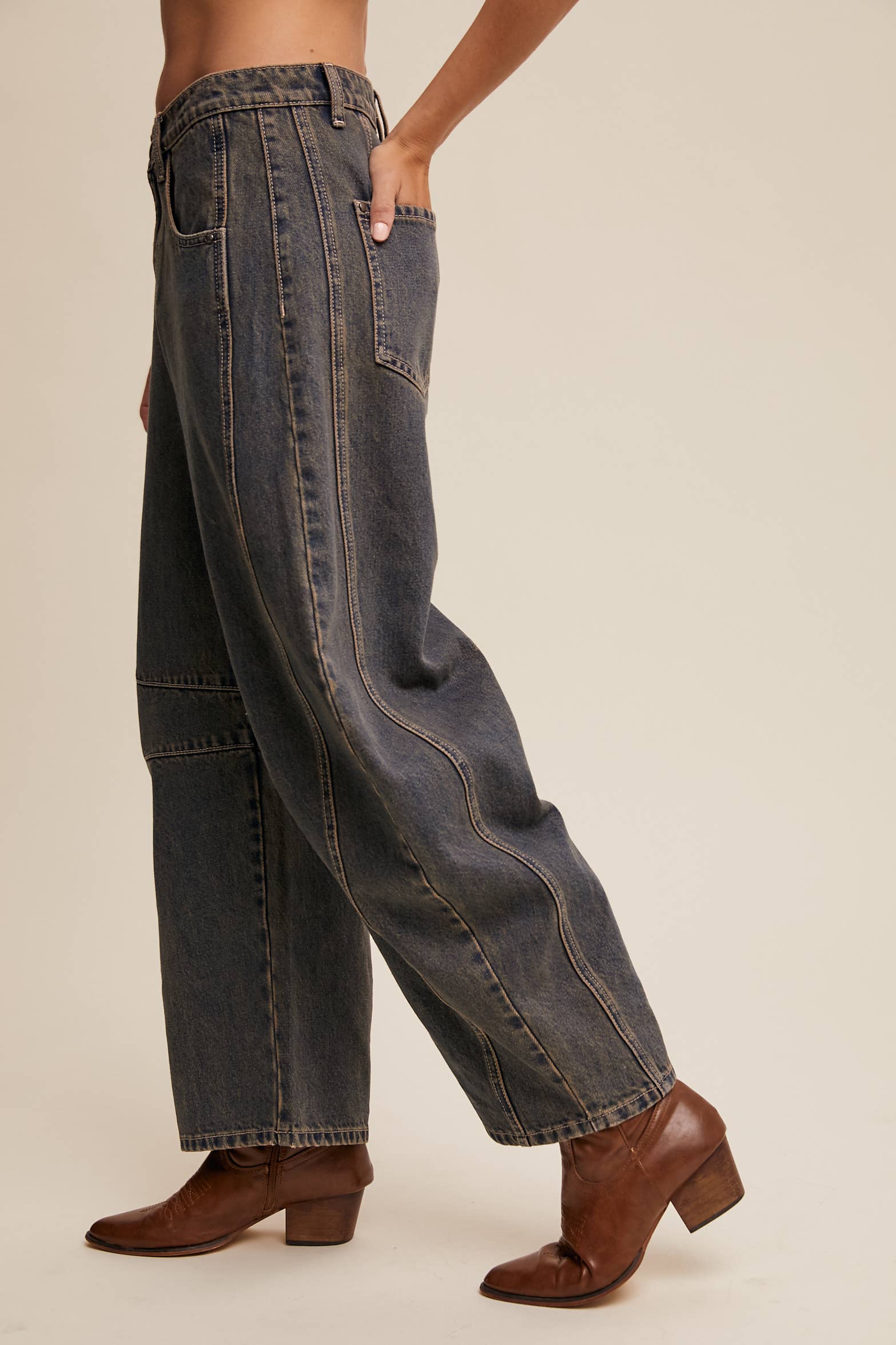 Side view- Dark wash wide-leg jeans with relaxed fit, seam detailing across the knees, and a high-rise waist, styled with brown ankle boots.